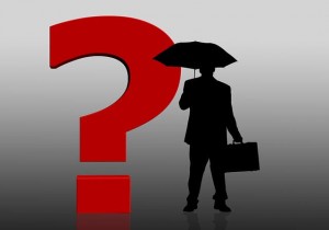 A man with an umbrella standing next to question mark.